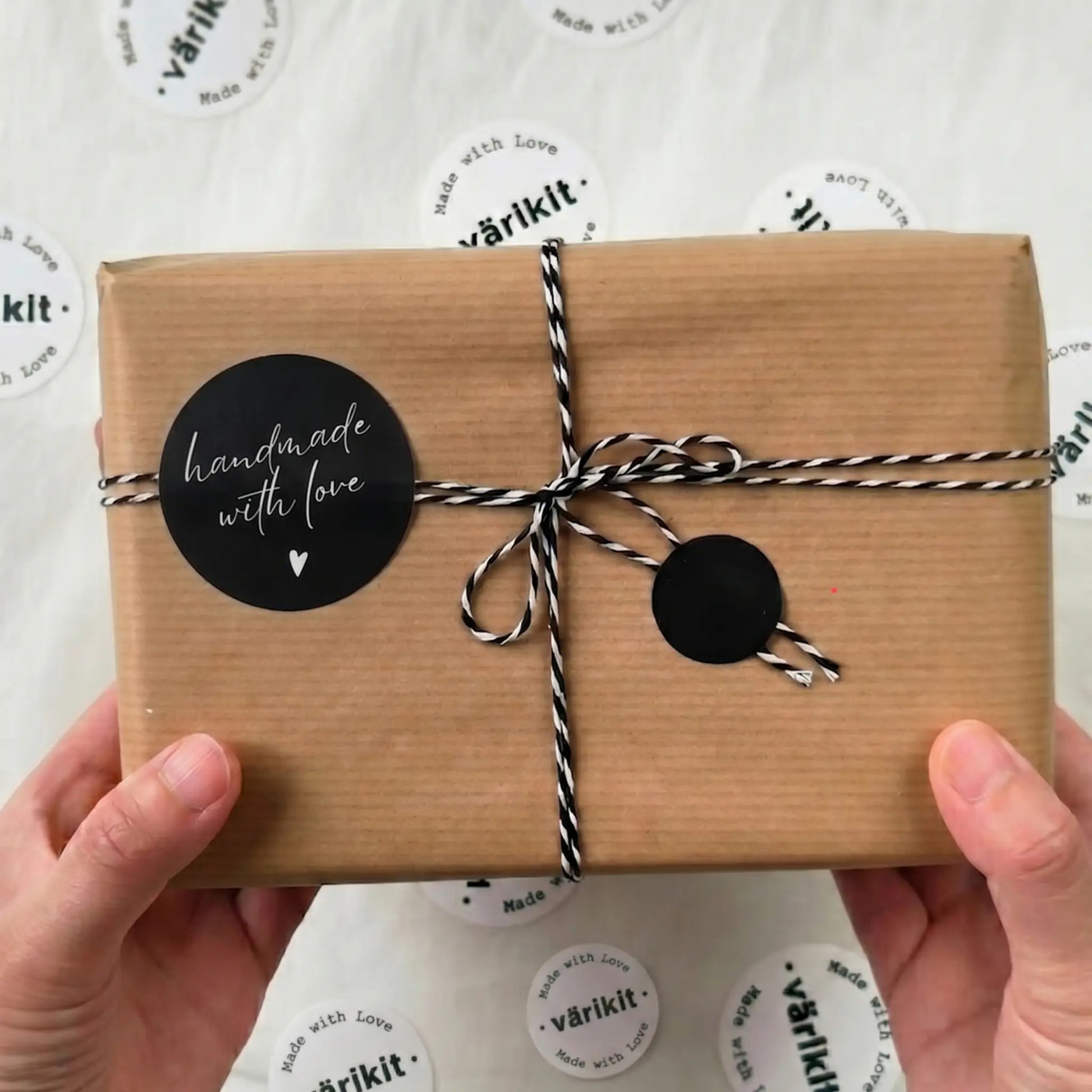 Gift box wrapped in brown paper with black 'handmade with love' label held by hands against a white background with 'värikit' branding.