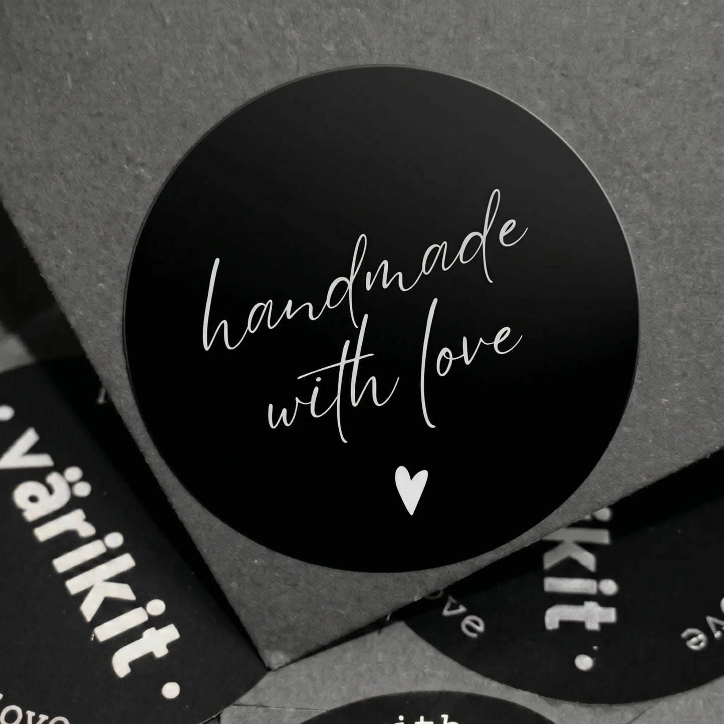 Black circular sticker with 'handmade with love' text on a gray background