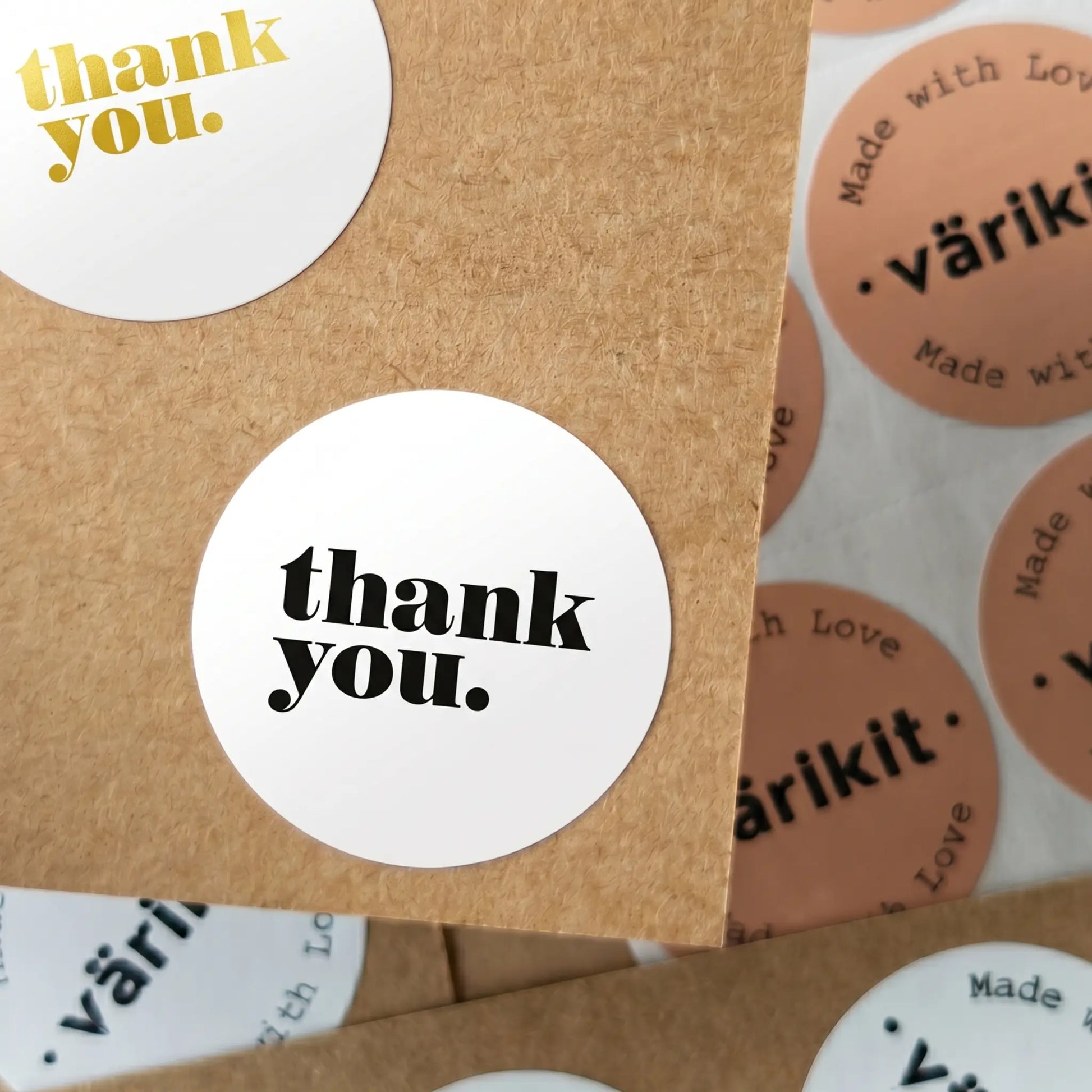 Round 'thank you.' stickers on a cardboard surface with 'värikit' branding.