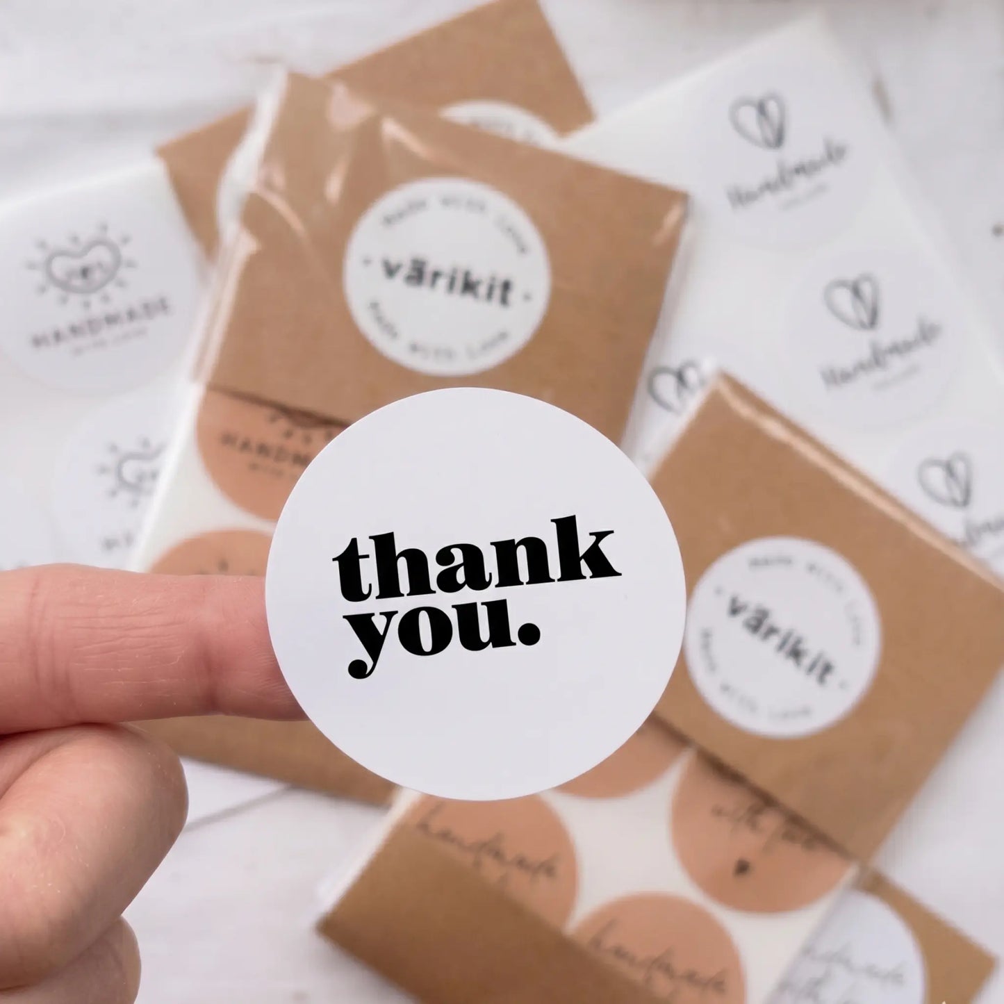 Hand holding a 'thank you.' sticker with Varikit products in the background