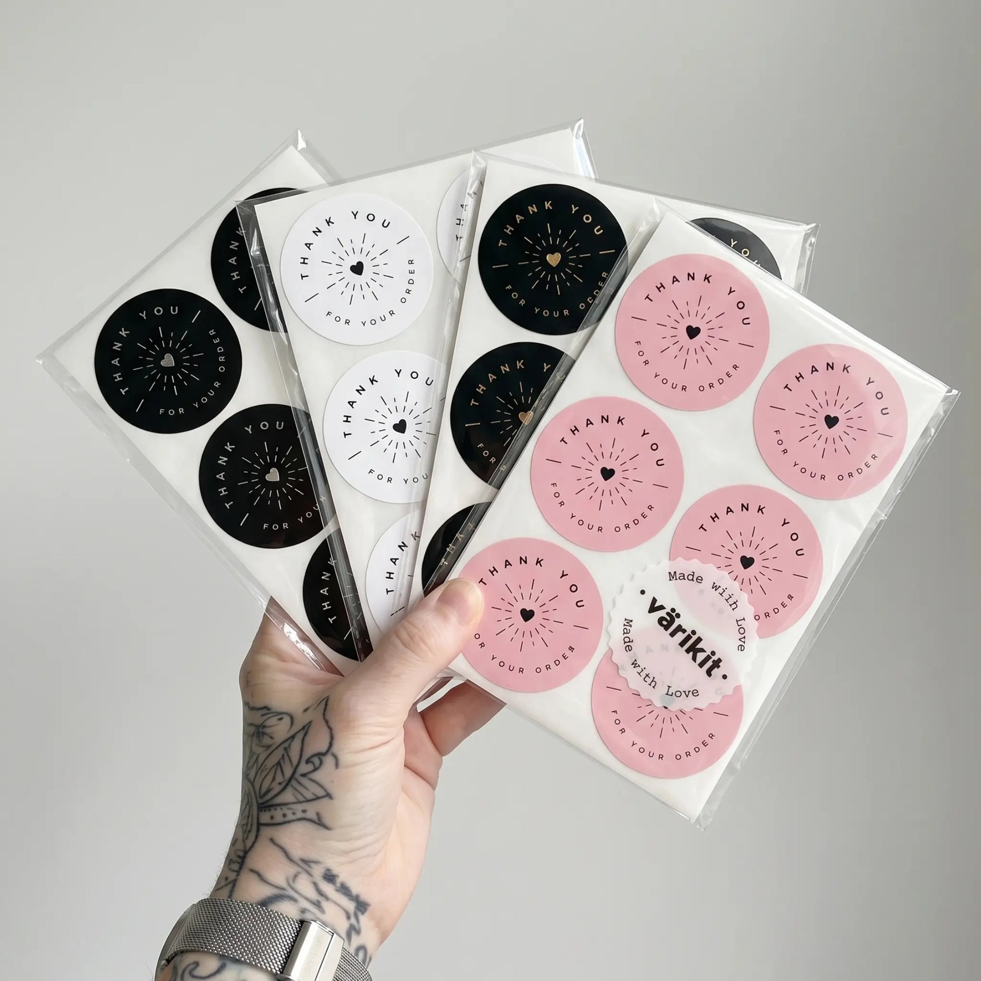 Hand holding packages of pink and black 'Thank You' stickers with visible 'varikit' branding.