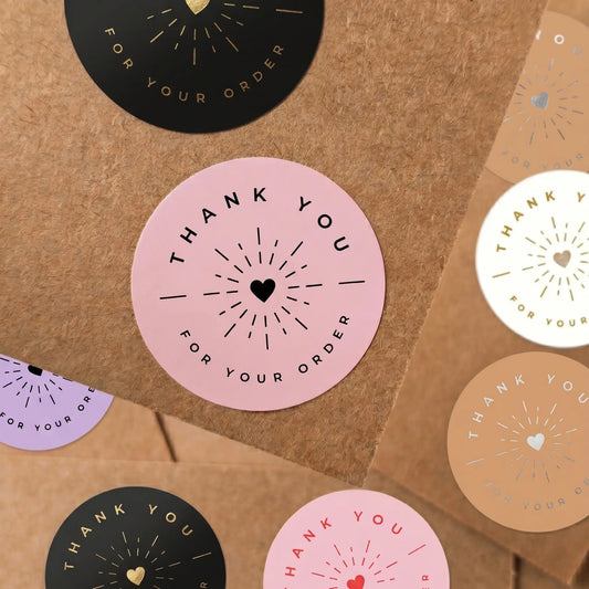 Round pink stickers with 'Thank you for your order' text on a brown paper background
