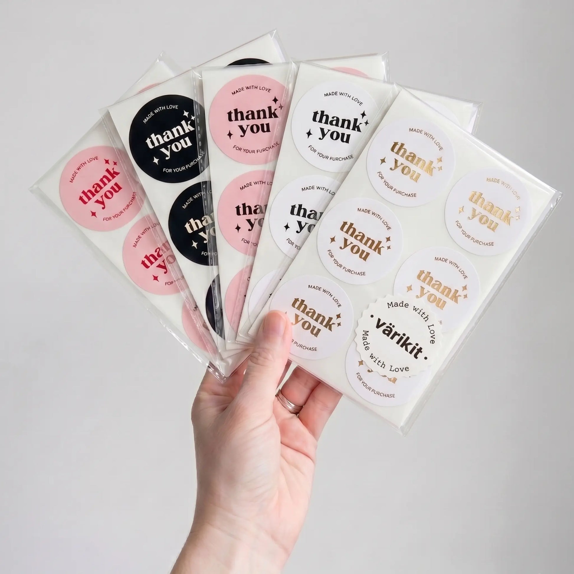 Hand holding packages of 'thank you' stickers with various designs.