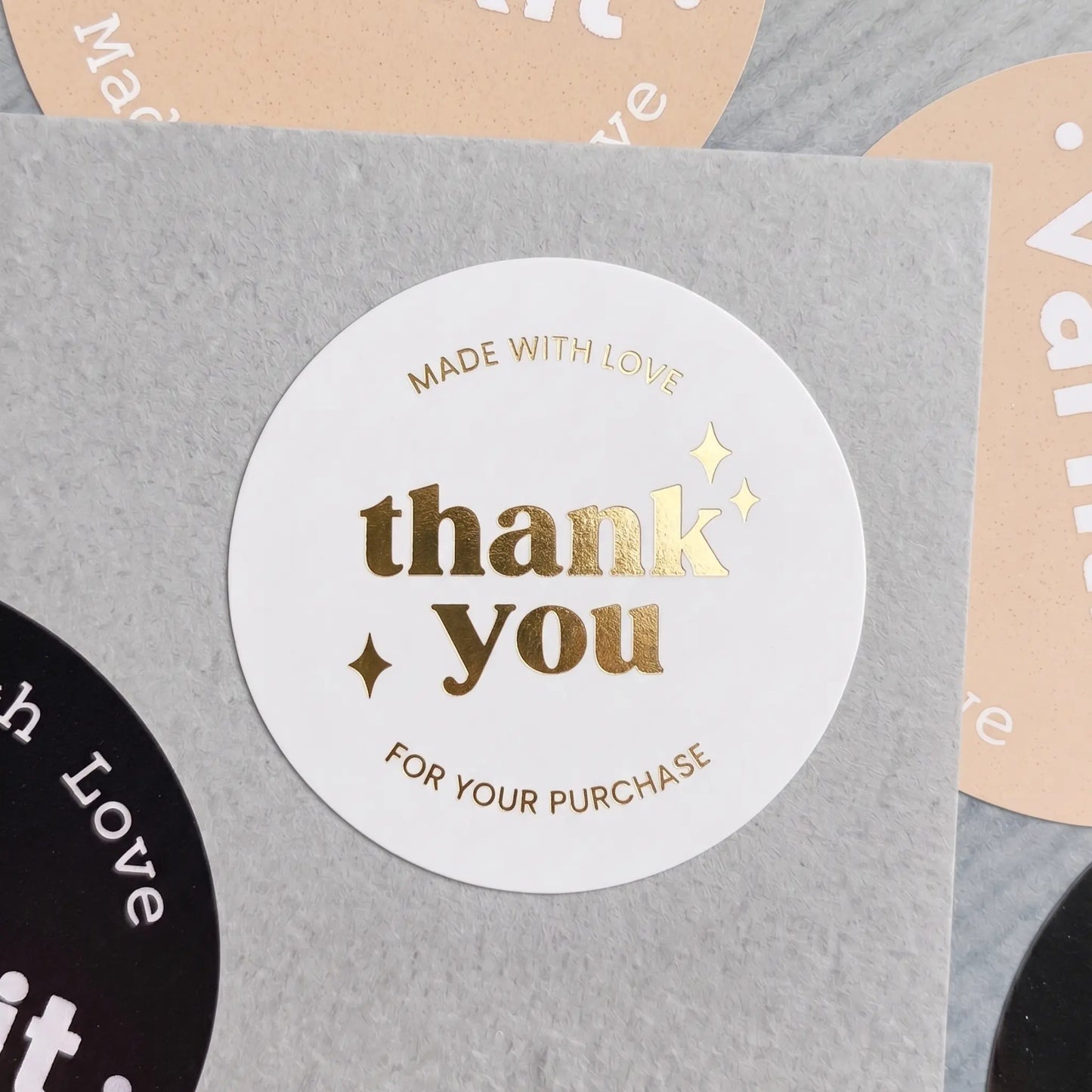 Round gold foil sticker with 'Thank you for your purchase' text on a gray background