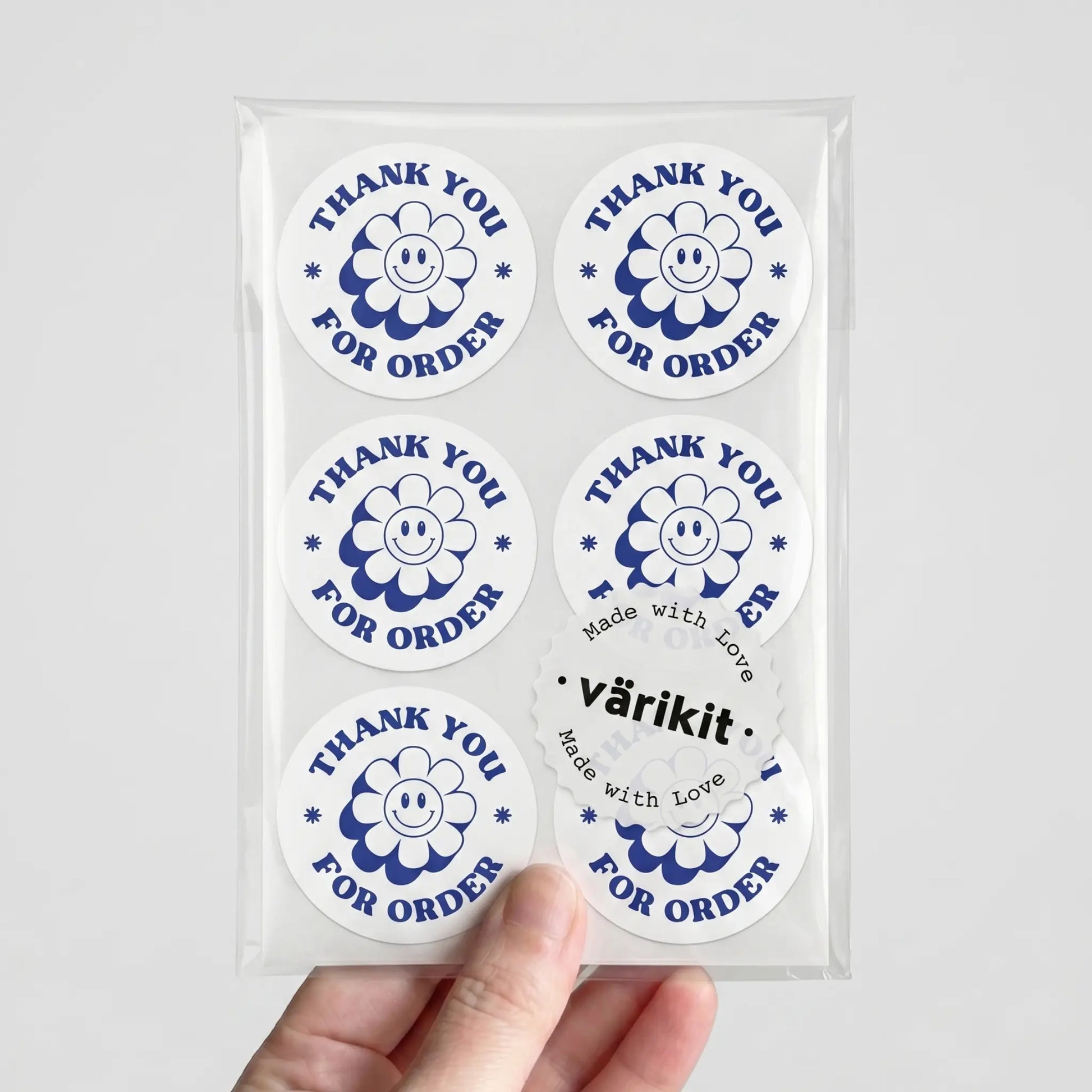 Packaged stickers with 'Thank you for order' text held by a hand on a light gray background