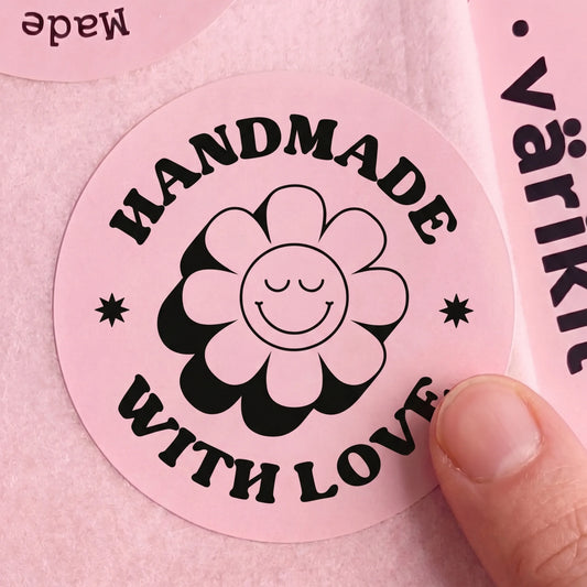 Pink label with 'Handmade with Love' and a flower design held by a hand on a pink background.