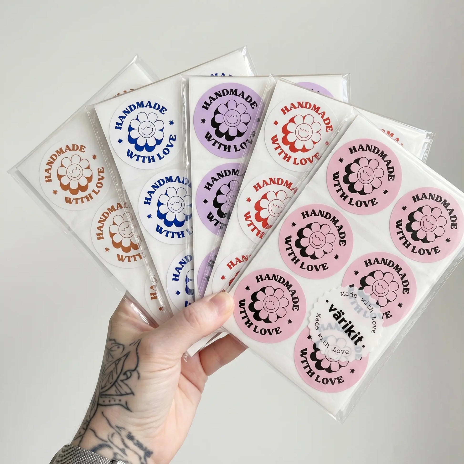 Handmade with Love stickers in various colors held by a hand on a light gray background