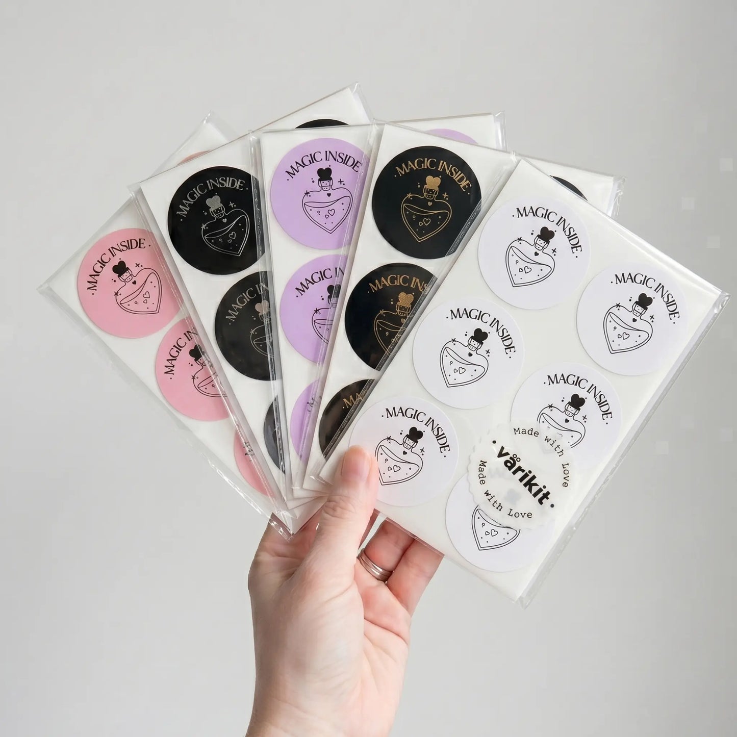 Hand holding multiple packages of 'Magic Inside' products on a light gray background