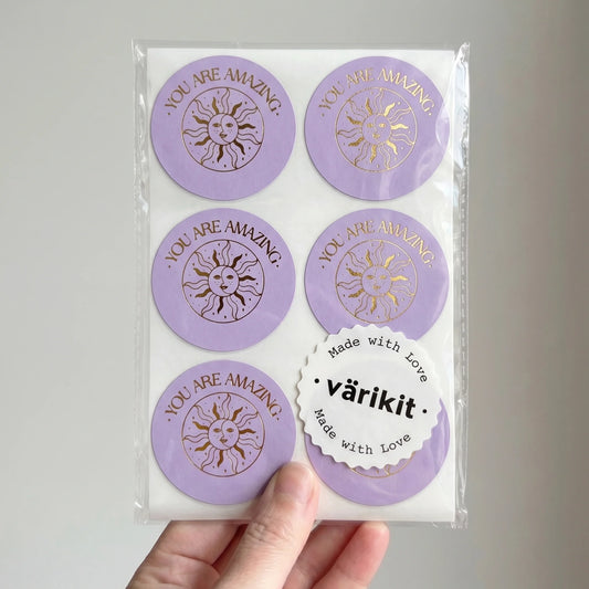 Hand holding a sheet of Thank You Smiling Sun Moon Varikit stickers reading 'YOU ARE AMAZING'.