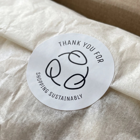Round paper seal marking eco-conscious orders with a distinct minimal identity.