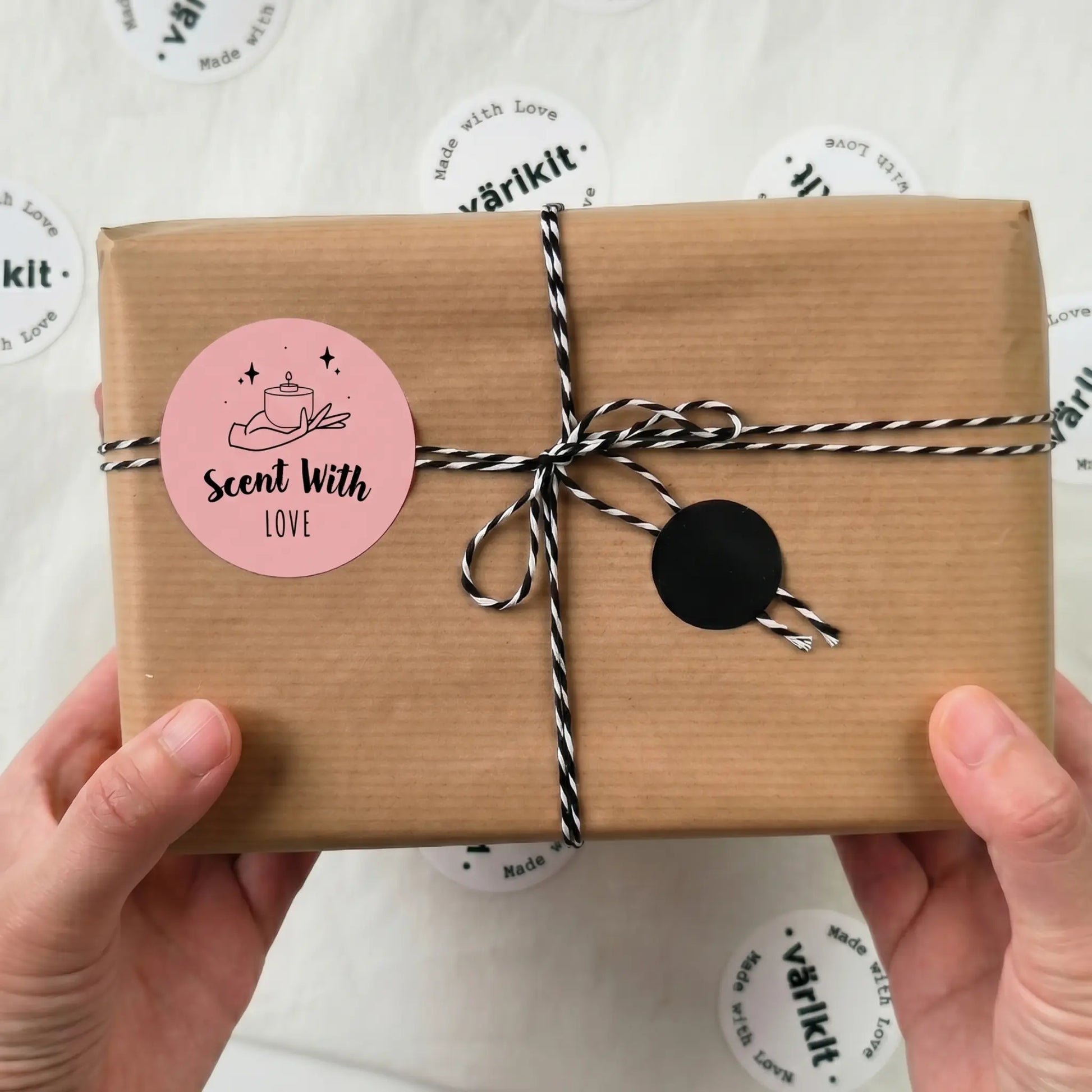 Gift box with brown paper wrap, pink 'Scent With Love' label, and black tie held by hands on a white background with 'varikit' branding.