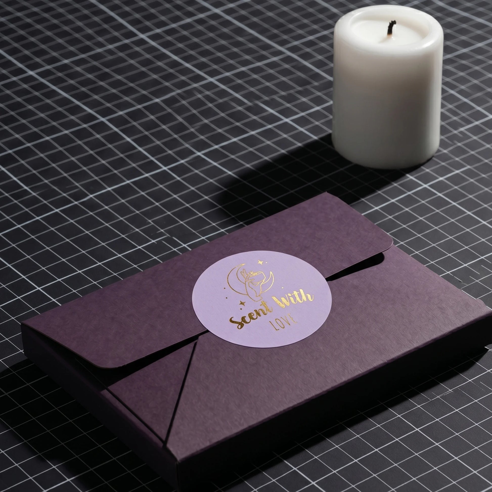 Purple cardboard mailer envelope sealed with a Scent With Love Mystic Candle Hand Varikit sticker reading 'Scent with Love' on a cutting mat.