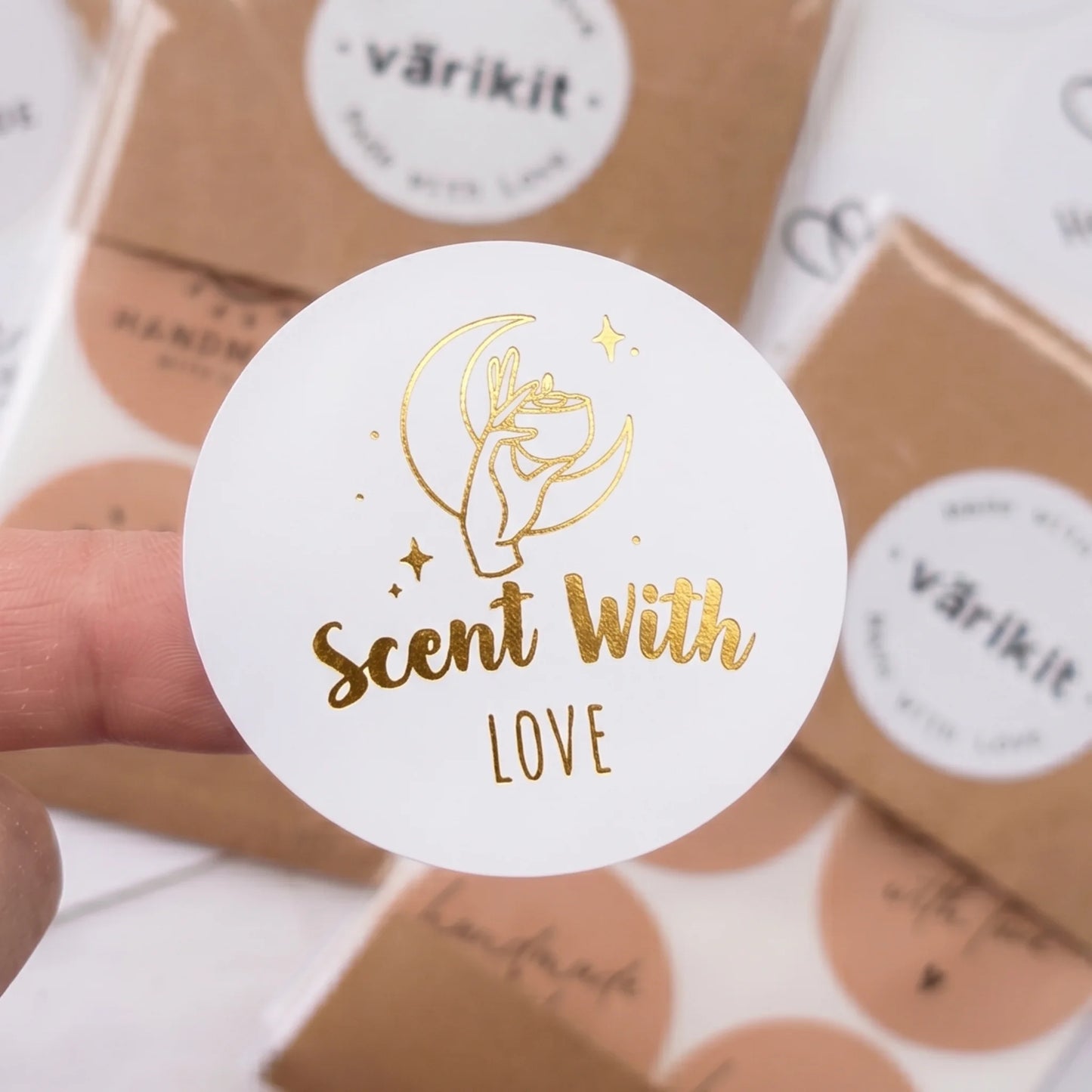 A hand holding a Scent With Love Mystic Candle Hand Varikit sticker reading 'Scent with Love' over other sticker sheets.