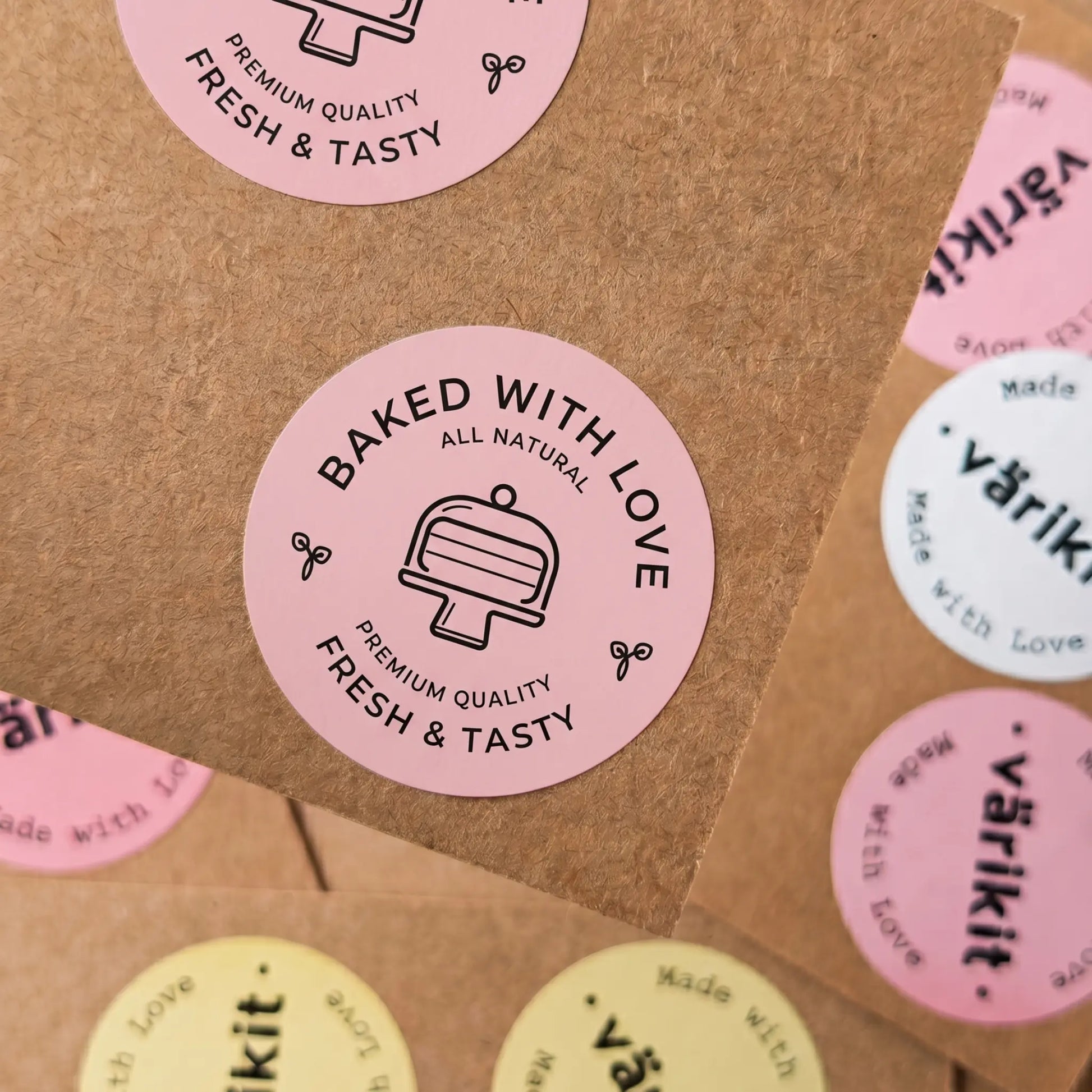 Pink round stickers with 'Baked with Love' text on a brown paper background