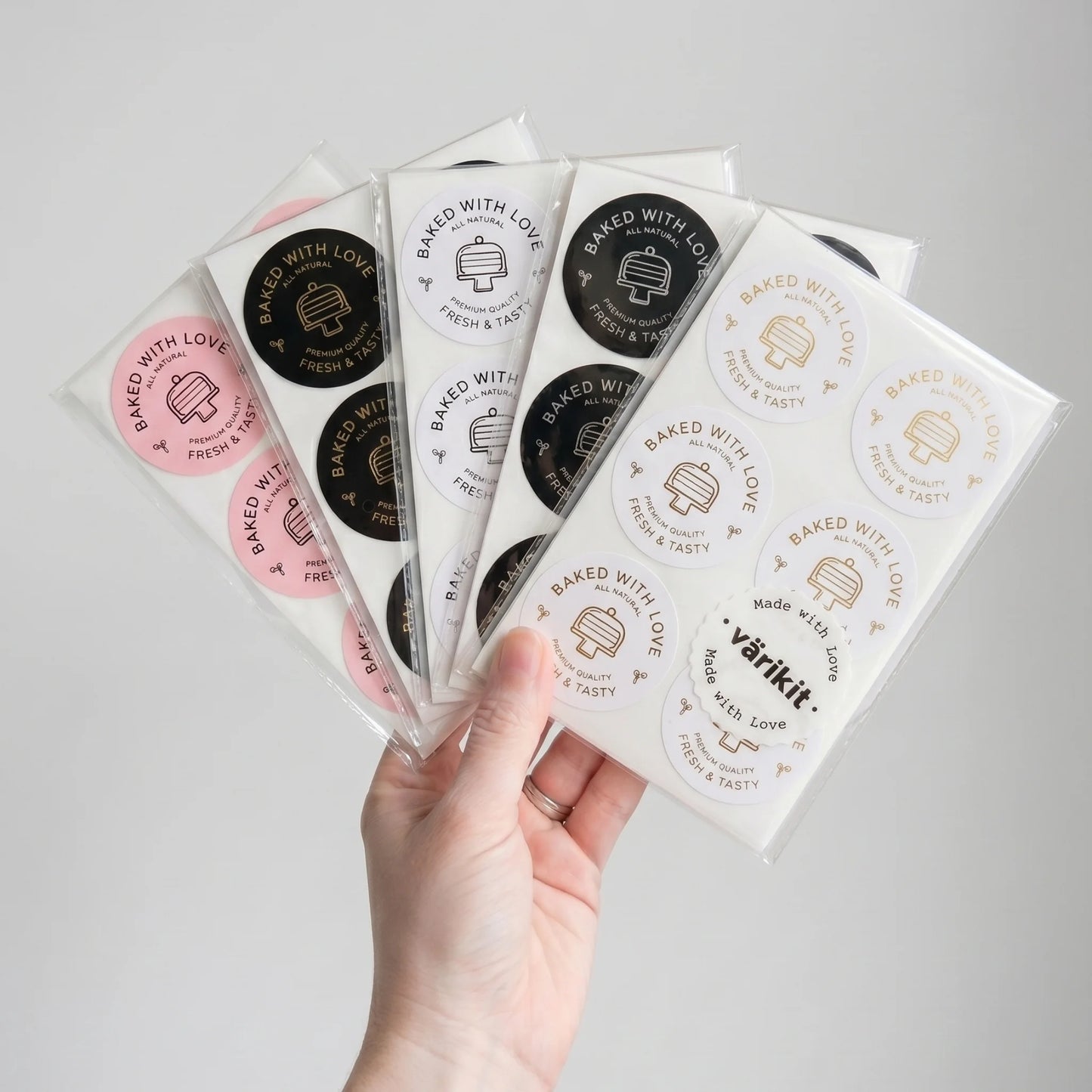 Hand holding multiple packages of 'varikit' baked goods ''baked with love' labels with visible branding.