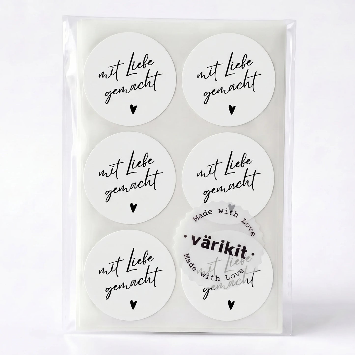 Set of round stickers with 'mit Liebe gemacht' text in a clear packaging on a white background