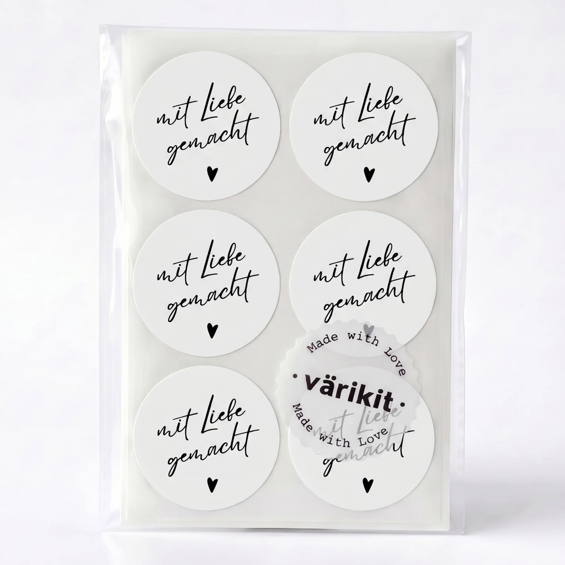 Set of round stickers with 'mit Liebe gemacht' text in a clear packaging on a white background