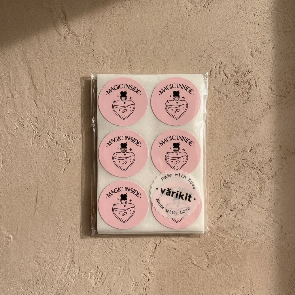 Varikit sealed pack of six pink circular 'Magic Inside' potion bottle stickers, secured with scalloped värikit brand label, on textured stone surface with natural sunlight shadows