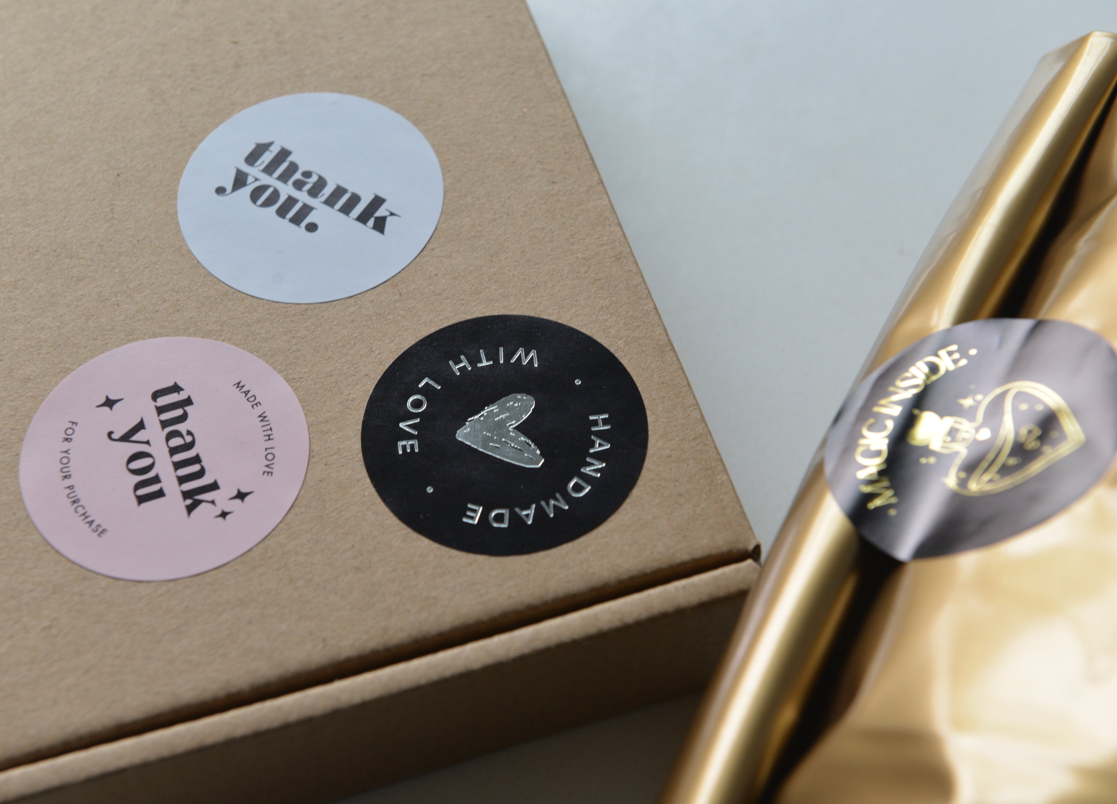 Varikit kraft box with circular pink and black thank you stickers, next to gold-wrapped package sealed with custom 'magic inside' branding label